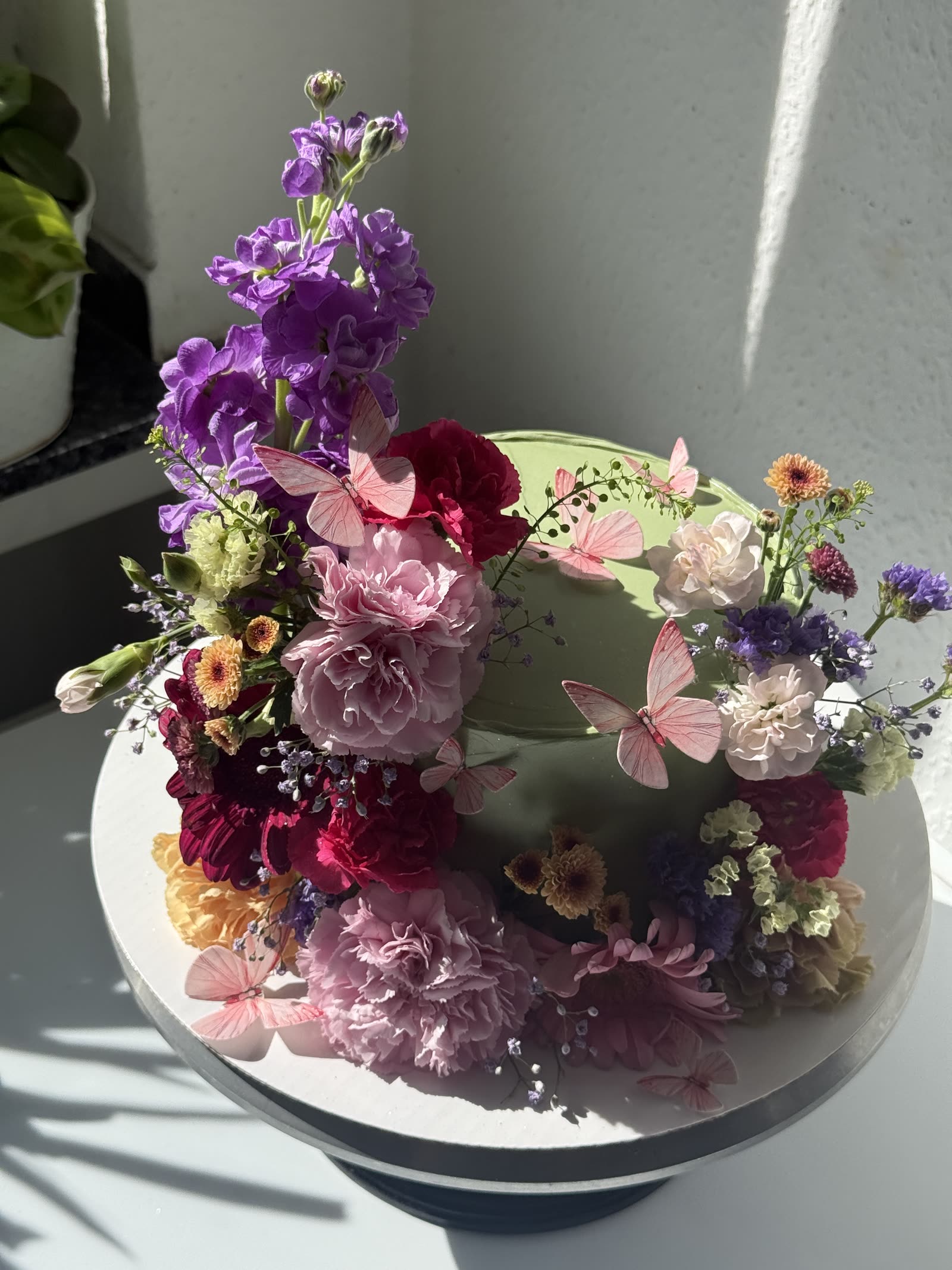 Pastellgrüne Kranztorte mit Nelken und Schmetterlingen