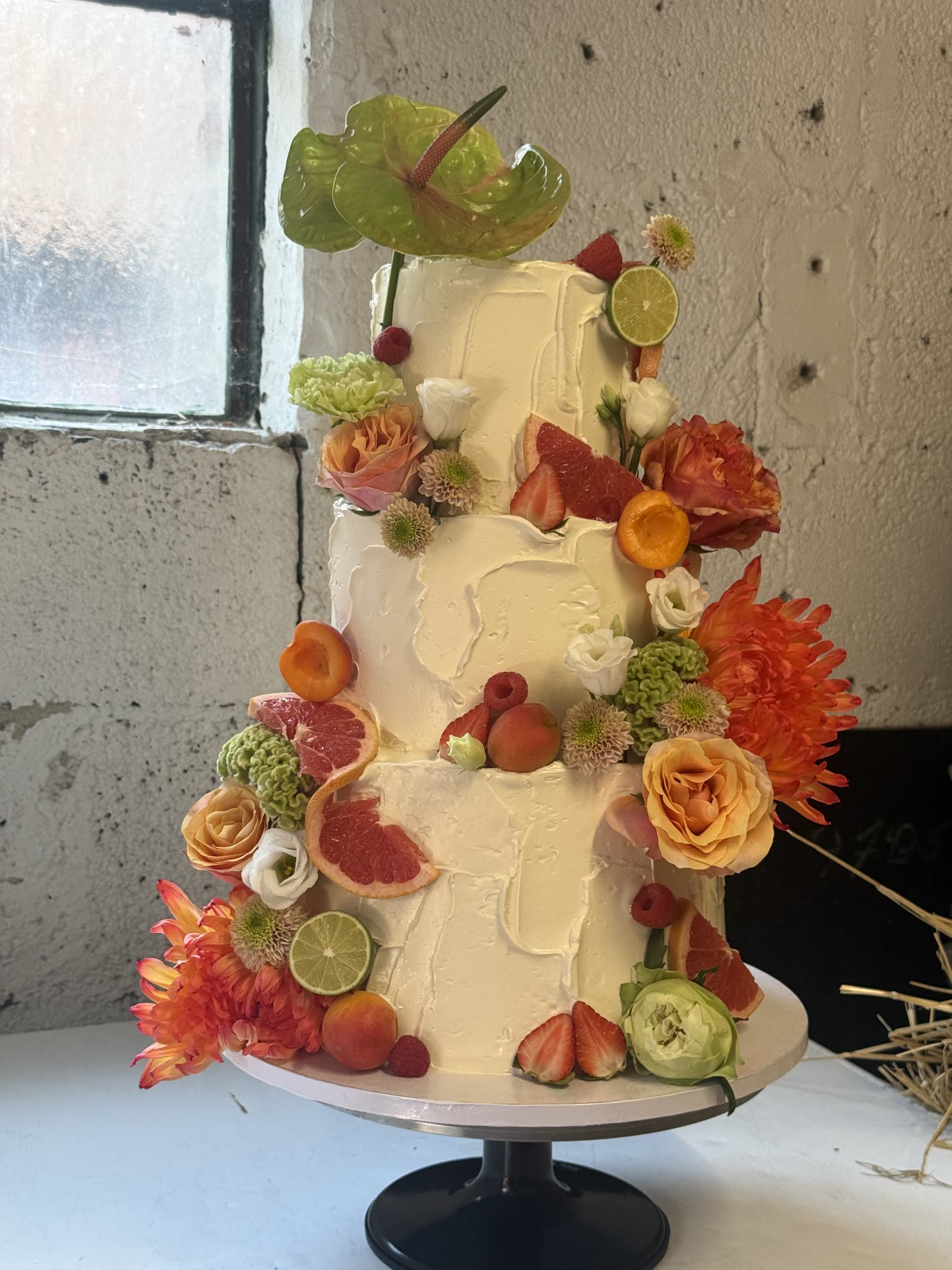 Dreistöckige Buttercreme-Torte mit Zitrusfrüchten und Erdbeeren