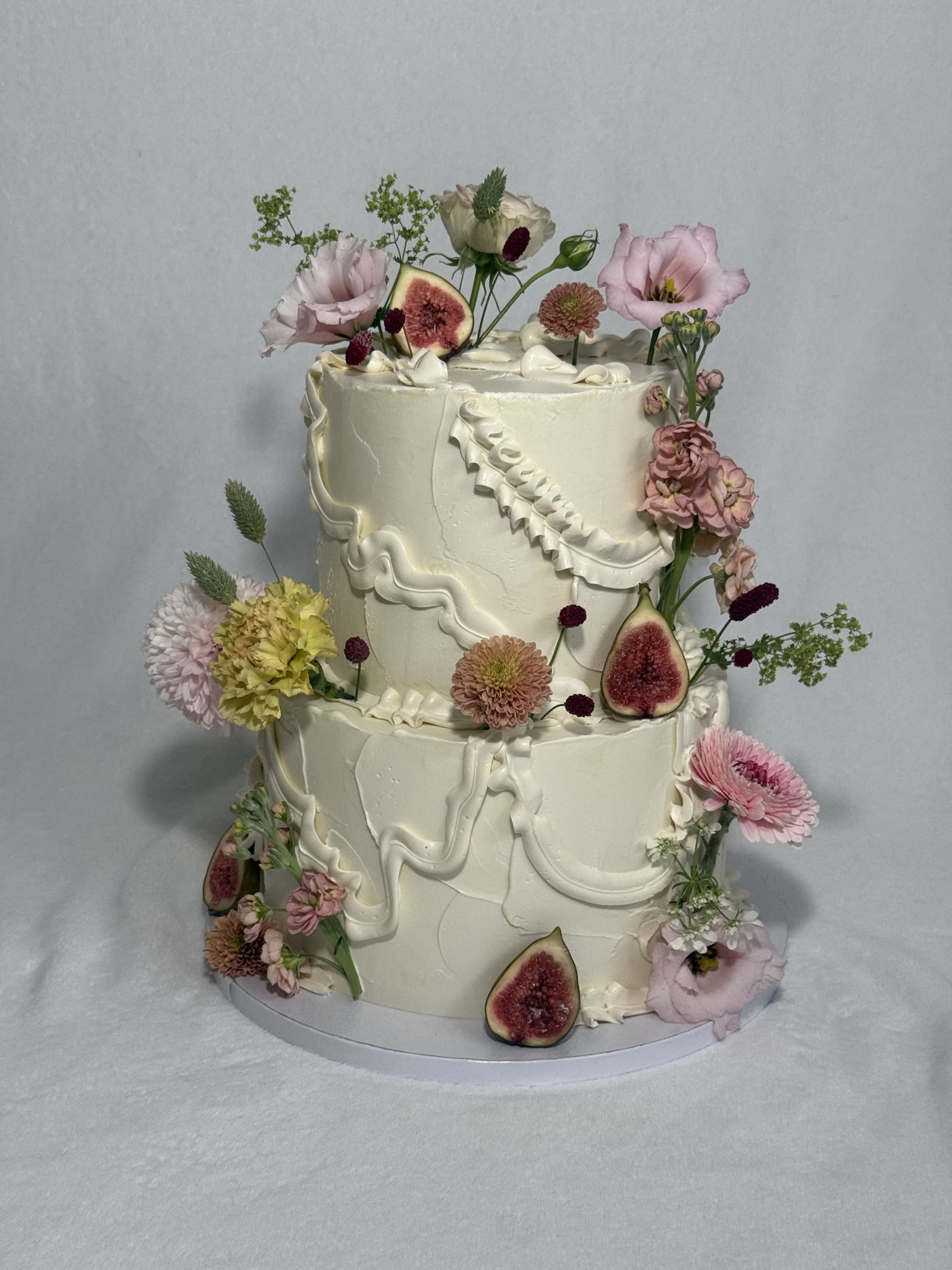 Zweistöckige Ivory-Torte mit rosa Blüten und frischen Feigen
